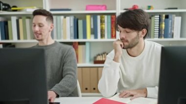 İki erkek öğrenci kütüphane üniversitesinde sessizce ders çalışmak istiyor.