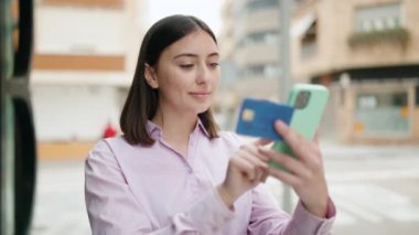 Genç İspanyol kadın akıllı telefon ve kredi kartı kullanıyor.