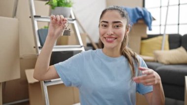 Genç ve güzel İspanyol kadın gülümsüyor. Yeni evin anahtarlarını göstererek kendine güveniyor.