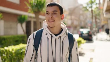 Sokakta kendinden emin gülümseyen genç bir öğrenci.