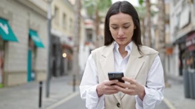 Sokakta gülümseyen akıllı telefon kullanan genç, güzel İspanyol kadın.