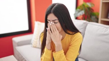 Evdeki kanepede oturan genç ve güzel İspanyol kadın stresli.