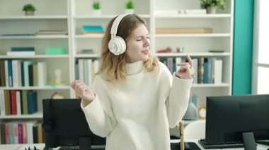 Young blonde woman student smiling confident listening to music at library university