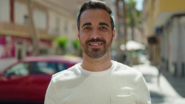 Young hispanic man smiling confident doing kiss gesture with hand at street