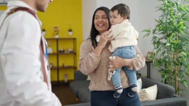 Çift ve oğul gülümseyerek klinikte kendinden emin bir şekilde el sıkışıyor