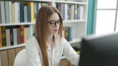 Young blonde woman student using computer stressed at university classroom