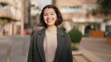 Genç İspanyol kız gülümsüyor. Kendine güveniyor. Sokakta elleriyle kalp hareketi yapıyor.