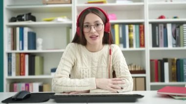 Genç, güzel İspanyol bir kız öğrenci kütüphane üniversitesinde video araması yaptığından emin gülümsüyor.