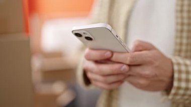 Genç Arap adam yeni evinde akıllı telefon kullanıyor.