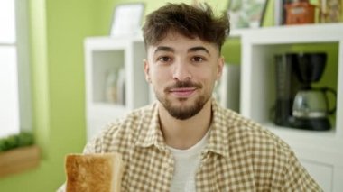 Genç Arap adam gülümsüyor evde tost tutarken kendinden emin.
