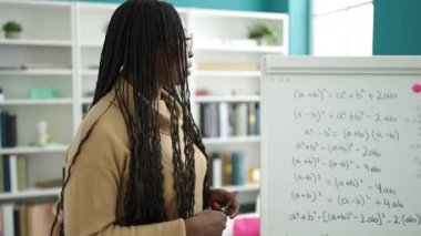 Afrikalı kadın kütüphane üniversitesinde manyetik tahtada matematik öğretiyor.