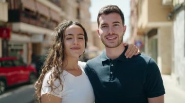 Genç İspanyol çift gülümsüyor. Sokakta birbirlerine sarılıyorlar.