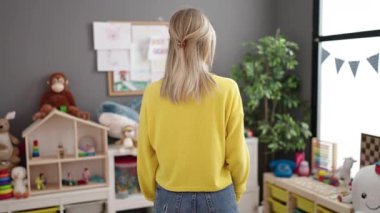 Young blonde woman working as teacher smiling happy at kindergarten