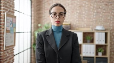 Genç ve güzel İspanyol iş kadını. Ofiste kollarını kavuşturarak gülümsüyor.