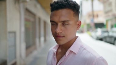 Young latin man smiling confident standing at street
