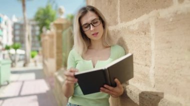 Sokakta kendine güvenen genç bir kadın kitap okuyor.