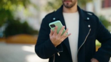 Genç İspanyol adam gülümsüyor. Parktaki akıllı telefondan konuşuyor.