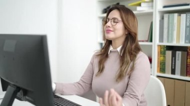 Young beautiful hispanic woman student doing yoga exercise at library university