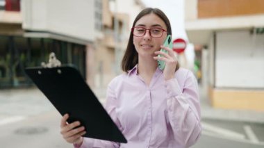 Genç İspanyol kadın akıllı telefondan konuşuyor. Sokaktaki dökümanları okuyor.