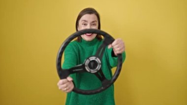 Olgun İspanyol kadın, gri saçlı, kendine güvenen, izole edilmiş sarı arka planda direksiyon kullanan.