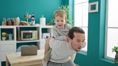Baba ve oğul yemek odasında birlikte dans ederken kendinden emin bir şekilde gülümsüyor.