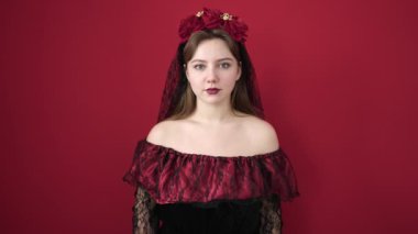 Young blonde woman wearing katrina costume doing scare gesture over isolated red background