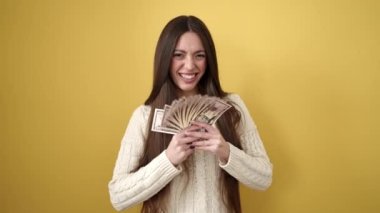 Genç, güzel İspanyol kadın gülümsüyor kendinden emin, izole edilmiş sarı arka plana dolar atıyor.