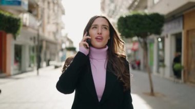 Genç İspanyol kadın gülümsüyor. Kendine güveniyor. Akıllı telefondan konuşuyor.