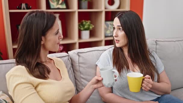 两个女人坐在沙发上喝咖啡 在家里讲话 — 图库视频影像