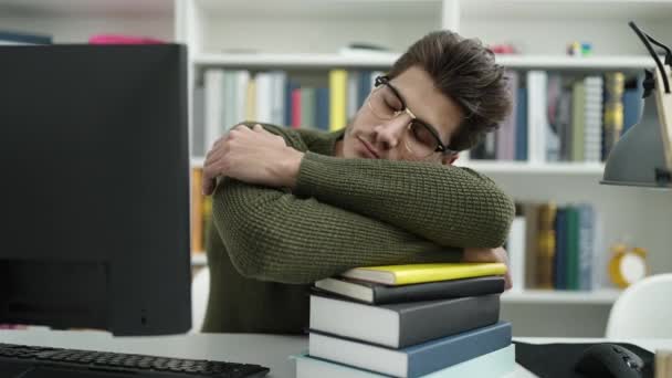 在图书馆大学 他的惊慌失措的年轻学生正把头靠在书本上睡觉 — 图库视频影像