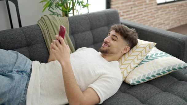 Jonge Arabier Man Met Smartphone Liggend Bank Thuis — Stockvideo