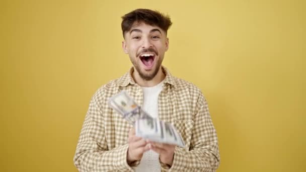 Młody Arabski Człowiek Uśmiechnięty Pewny Siebie Rzucanie Dolarów Odizolowanym Żółtym — Wideo stockowe