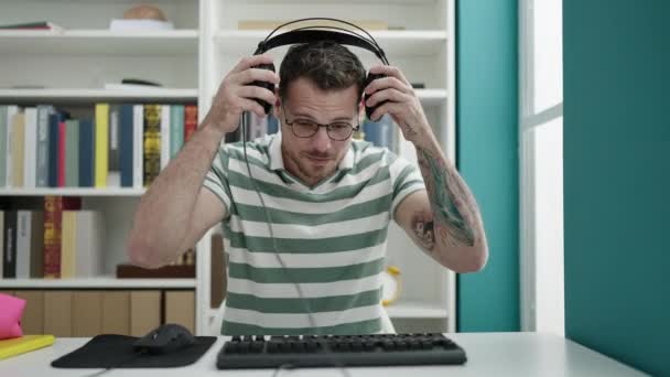 Młody Biały Człowiek Pomocą Komputera Noszącego Słuchawki Uniwersytecie Bibliotecznym — Wideo stockowe
