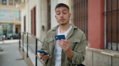 Genç İspanyol adam akıllı telefon ve kredi kartı kullanıyor.