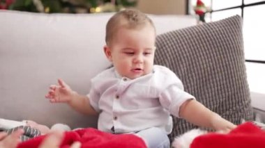 Evdeki Noel ağacının yanında kendine güvenen sevimli bir çocuk oturuyor.