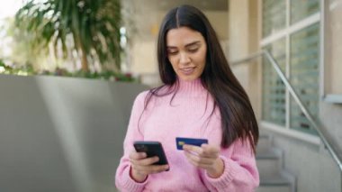Genç İspanyol kadın akıllı telefon ve kredi kartı kullanıyor.