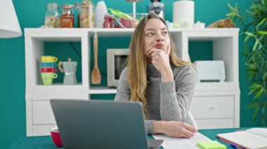 Kafkasyalı genç bir kadın yemek odasında dizüstü bilgisayar kullanıyor.