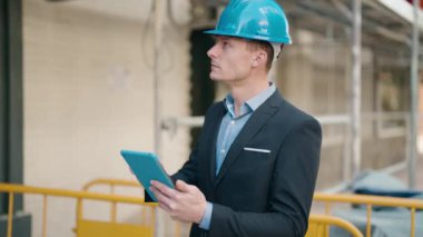 Young caucasian man architect with relaxed expression using touchpad at street