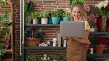 Young beautiful hispanic woman florist smiling confident using laptop at flower shop