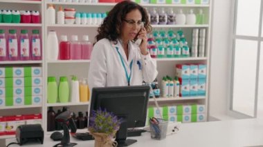 Eczanede telefonla konuşan orta yaşlı kadın eczacı.