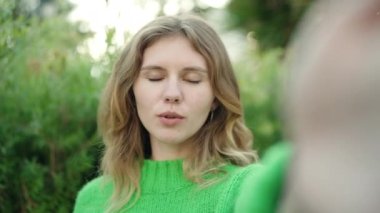 Young blonde woman smiling confident having video call at park