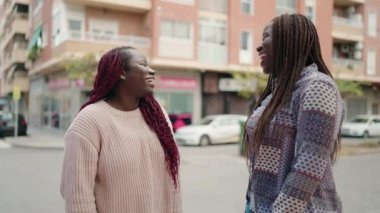 Two african american women smiling confident hugging each other at street