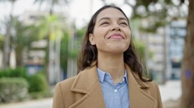 Genç, güzel, İspanyol bir kadın. Parkta kazanan yüz ifadesiyle duruyor.