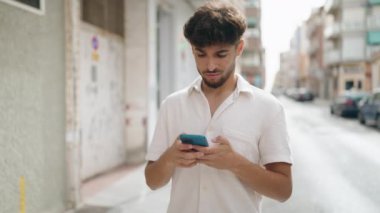 Young arab man using smartphone with winner expression at street