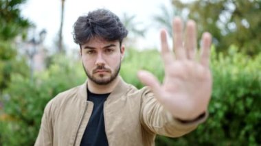 Genç İspanyol adam parkta el hareketlerini durduruyor.