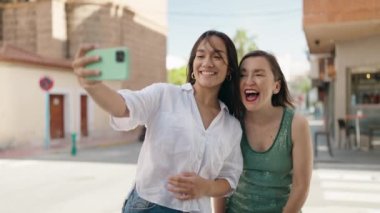 Two women mother and daughter make selfie by smartphone at street