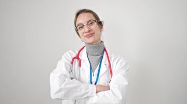 Beyaz arka planda kollarını kavuşturup gülümseyen genç beyaz kadın doktor.