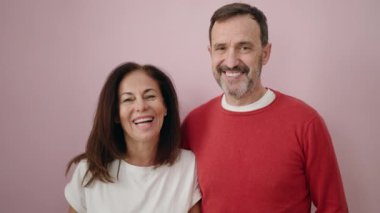 Erkek ve kadın çift pembe arka planda birbirlerine sarılıyorlar.