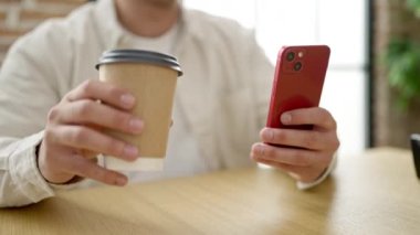 Genç İspanyol iş adamı akıllı telefon kullanıyor. Ofiste kahve içiyor.
