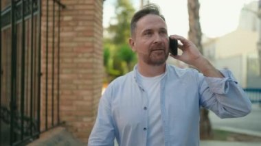 Kafkasyalı genç adam gülümsüyor. Kendine güvenen caddedeki akıllı telefondan konuşuyor.